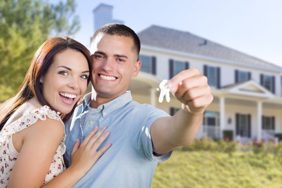 Couple holding keys in front of house